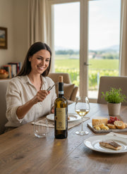 Frau öffnet eine Flasche Zeni Lugana DOC Marogne 2025 Weißwein mit einem Korkenzieher, serviert mit Käse und Fisch.